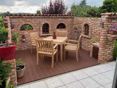 U-förmige Gartenmauer aus historischen Backsteinen im Ruinenstil mit kleinen Rundbogenöffnungen.